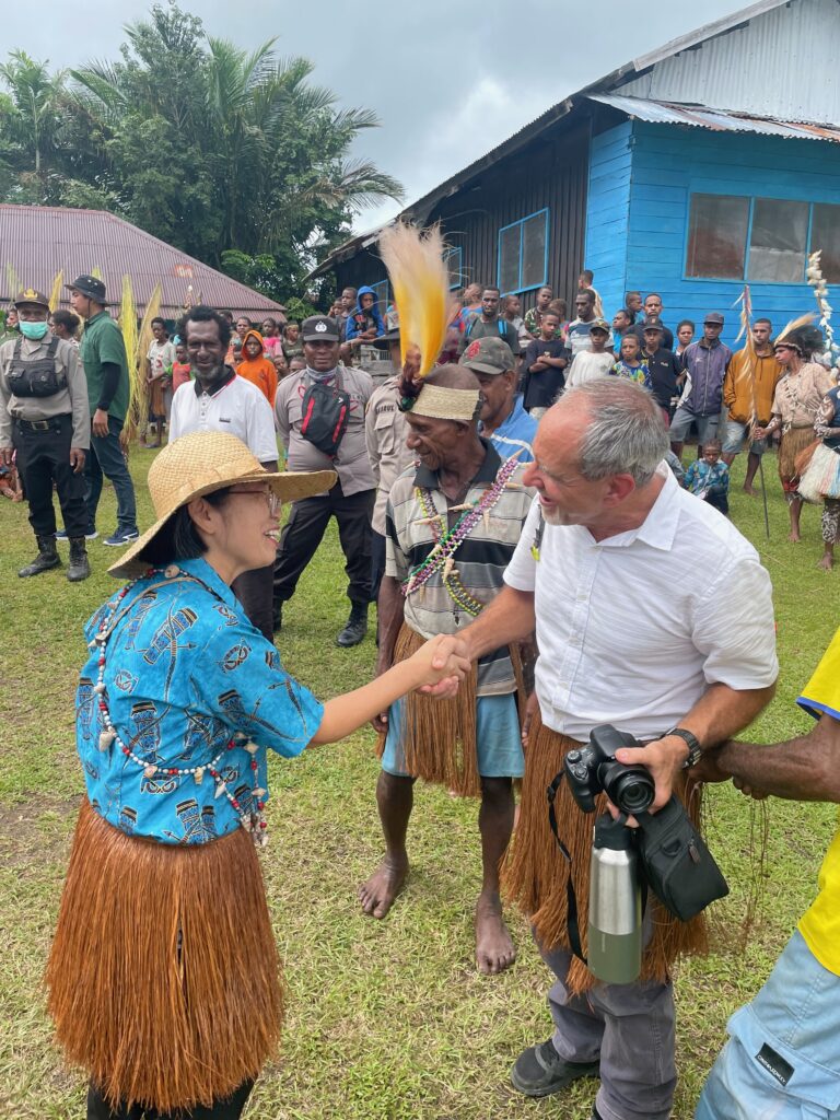 MyoSook welcomes MAF pilot Tom Bolser during the dedication of the New Testament in the Central Auyu language in Kotiak, Indonesia